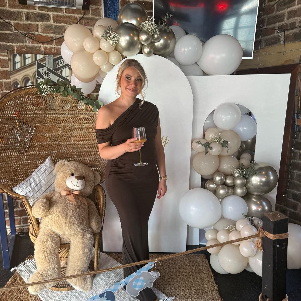 baby-shower-sign-and-balloon-display Woman smiling at her baby shower in front of an elegant Elpresents bespoke sign and balloon display