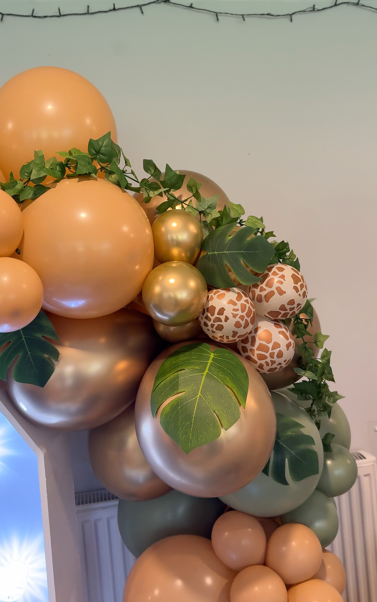 Gold and green balloons and foliage at a jungle-themed childrens party