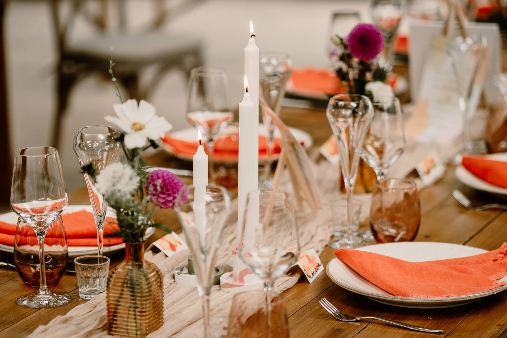 Rustic burnt orange wedding table decoration with candles, flowers, and glassware
